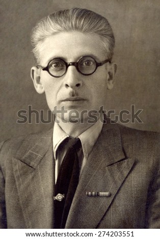 Russia, - CIRCA 1950s: An antique studio portrait of middle-aged man in a business suit, and glasses