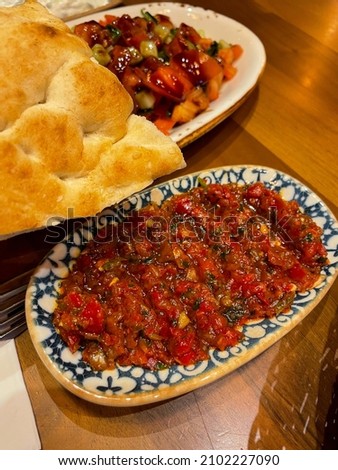 Traditional turkish spicy dip acili Ezme with red paprika pepper, tomatoes, onion and spices in small decorative plate and pide bread in turkish restaurant Stok fotoğraf © 