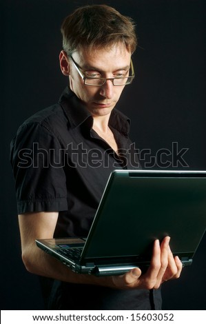man on black background peers into computer