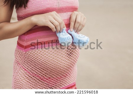 Pregnant woman in white bikini posing on the beach