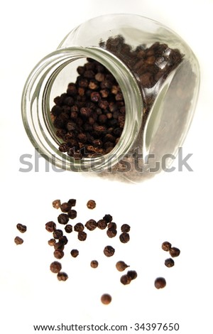 Glass jar with black peppercorns inside and outside, no cover, on the side. Isolated on white