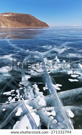 Baikal Lake in winter. White bubbles and cracks in transparent ice