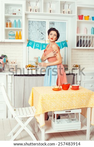 Pin-up girl style. Girl in retro style stands in the kitchen and holding a bottle.