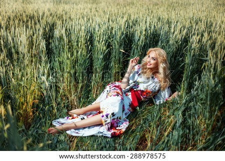 Girl in the field with ears of corn in his hand. She in a summer dress. She dreams of romance.