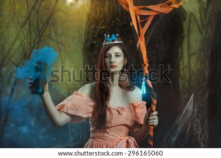Girl fairy in the magical forest. In the hands holding blue smoke.