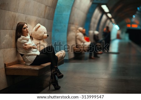 Girl is sad sitting on the bench. Away blurred people.