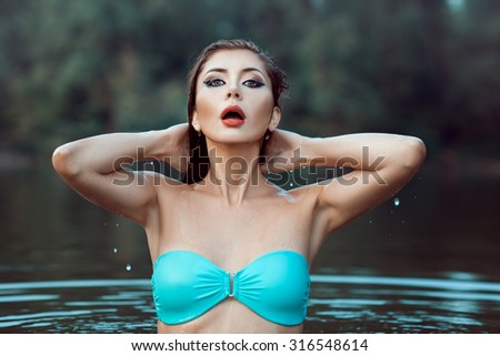 Girl in a bathing suit emerged from the water. She wet and dripping drops.