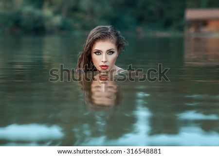 Girl\'s face peeking out of the water.  Girl is resistant to water makeup.