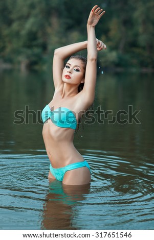 Beautiful girl standing in the lake water. Her wet body.