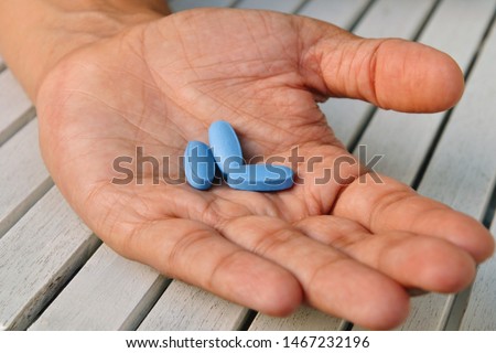 Hand of man holding blue pills. Closeup of a young man with a blue pills in one hand. Blue medicine pills. Medicine concept of viagra, medication for stomach, erection, sleeping, digestive, drugs Сток-фото © 
