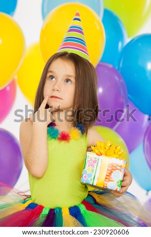 Happy little kid girl with gift box and colorful balloons on birthday party. Holidays, birthday concept.