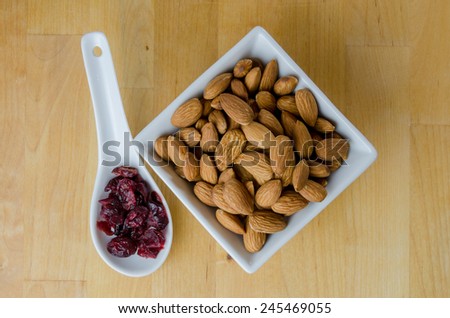 Ceramic spoon and bowl hold dried cranberries and heart healthy almonds