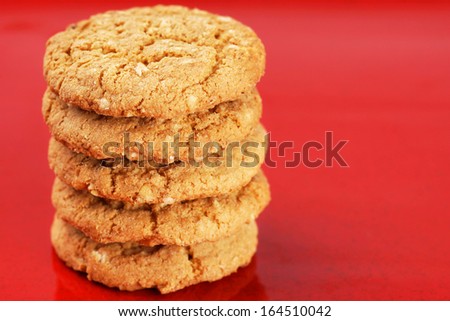 Stack of homemade peanut butter and oatmeal cookies on red enamel background