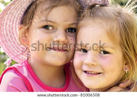 Real life cousins, two happy little girls hugging outside on a beautiful sunny day, best friends forever.