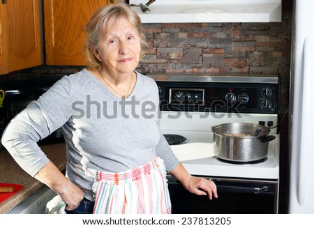 Friendly smiling grandmother or senior woman cooking in her kitchen