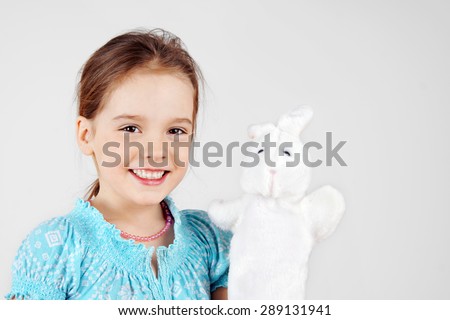 Cute little girl playing with rabbit hand puppet