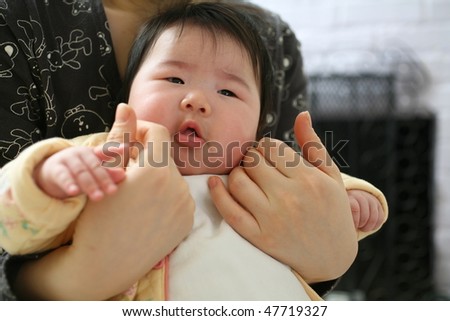 Beautiful Asian Baby Girl in yellow bodysuit being held