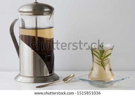 Rosemary tea in Armudu glass with branch of rosemary in it, teapot and spoon on the table on the white background Photo stock © 