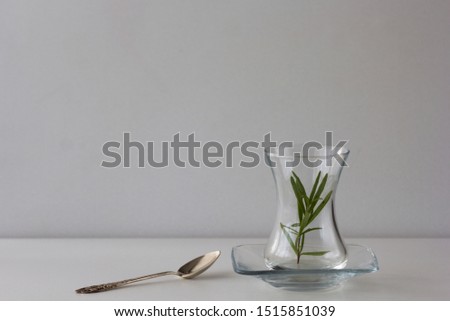 Empty Armudu tea glass with branch of rosemary in it and spoon on the table on the white background Photo stock © 