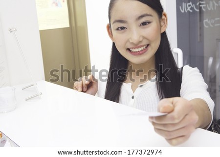 Japanese dental patient submitting patient registration card at the dentist
