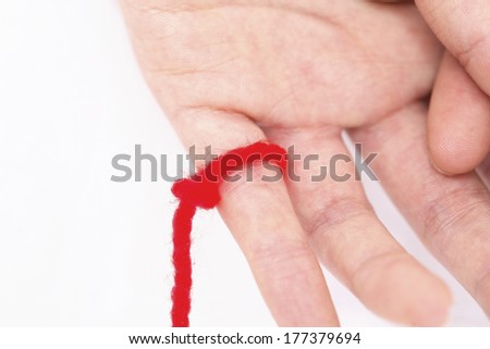Red string of wool around finger