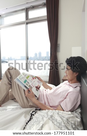 Japanese man reading a magazine and lying down in bed