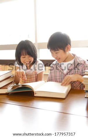 Primary Japanese boy and Japanese girl who read a book in the library