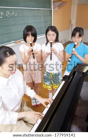 Primary Japanese students blow the recorder in the music room