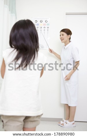 Nurse performing a visual acuity test for girl