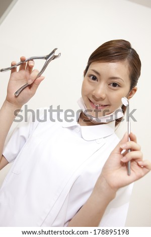 Dental Japanese hygienist smiling with a pliers and oral cavity mirror