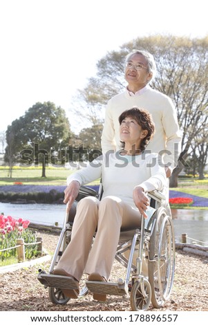 Senior Japanese man pushing his wife in a wheelchair