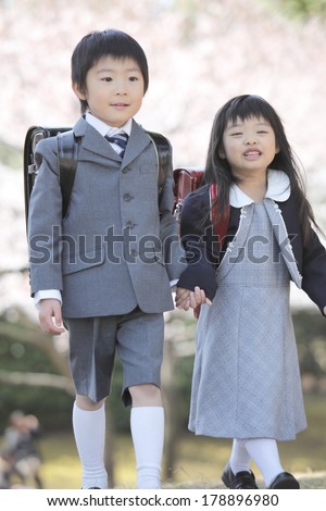 Japanese boy and Japanese girl in school uniform walking under the cherry tree