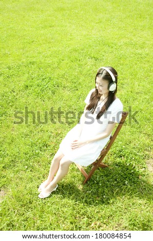 Japanese woman listens to music in a meadow