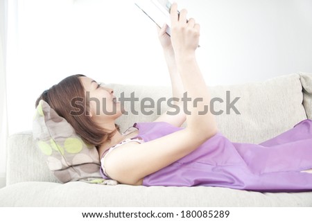 Japanese woman reading a book while lying on the sofa in a nightgown