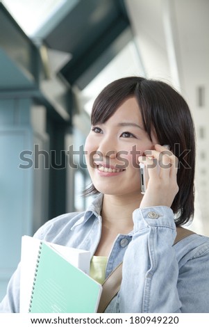 A Japanese student talking on her phone with a smile,