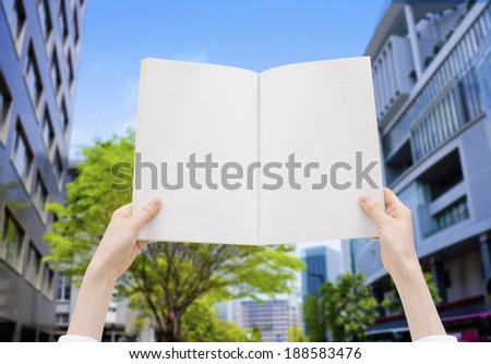 Person holding white book in the city