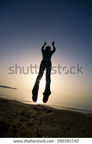 Woman jumping on beach during sunset