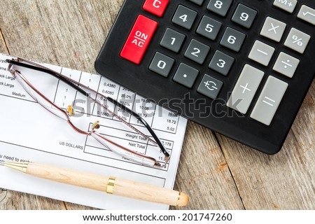 Invoice with balance due, calculator,pen and glasses