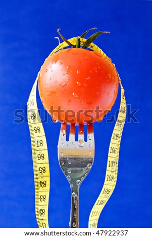 concept for healthy food. fork with tomato and measure tape