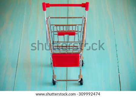 Empty mini shopping cart against wooden background