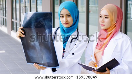 Two young doctors examining a file in in front of hospital