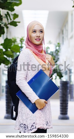 Beautiful young muslim student holding a file and backpack