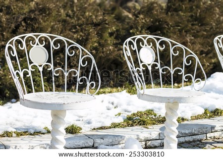 The empty white iron chairs in winter park