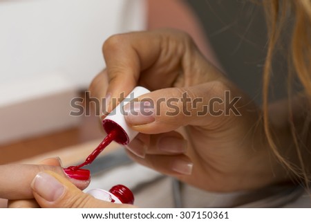 Manicure in the spa salon. Drawing of red nail polish. Spa manicure, nail care. Girl does a manicure. The concept of hand care.