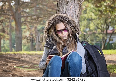 Portrait of attractive young girl with book in a park