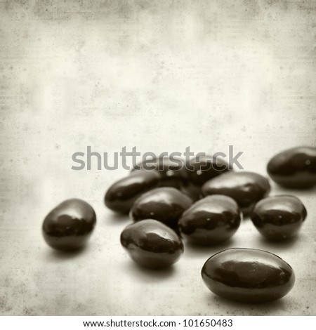 textured old paper background with chocolate coated almonds