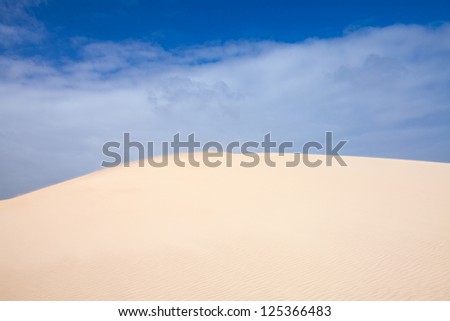 sand and sky dunes abstract, edge of the dune blurred by flying sand