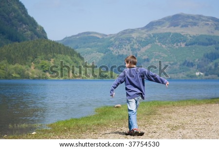 Little boy is throwing stones in the water, Loch Lubnaig - moment after the throw
