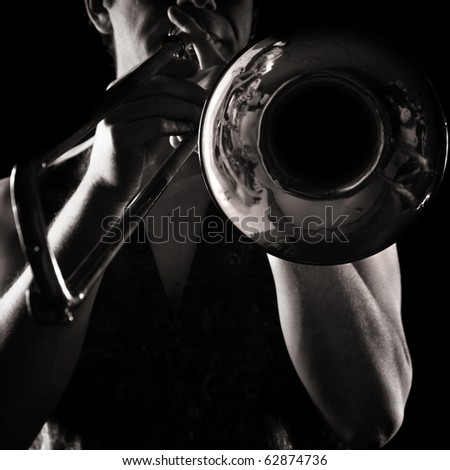 man playing a trombone; strong contrasting side-light; monochrome version;