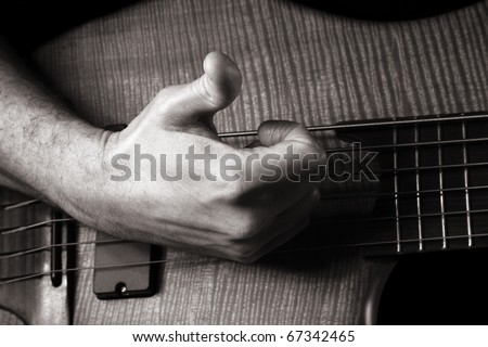 playing six-string electric bass guitar; slap technique, right hand; toned monochrome image